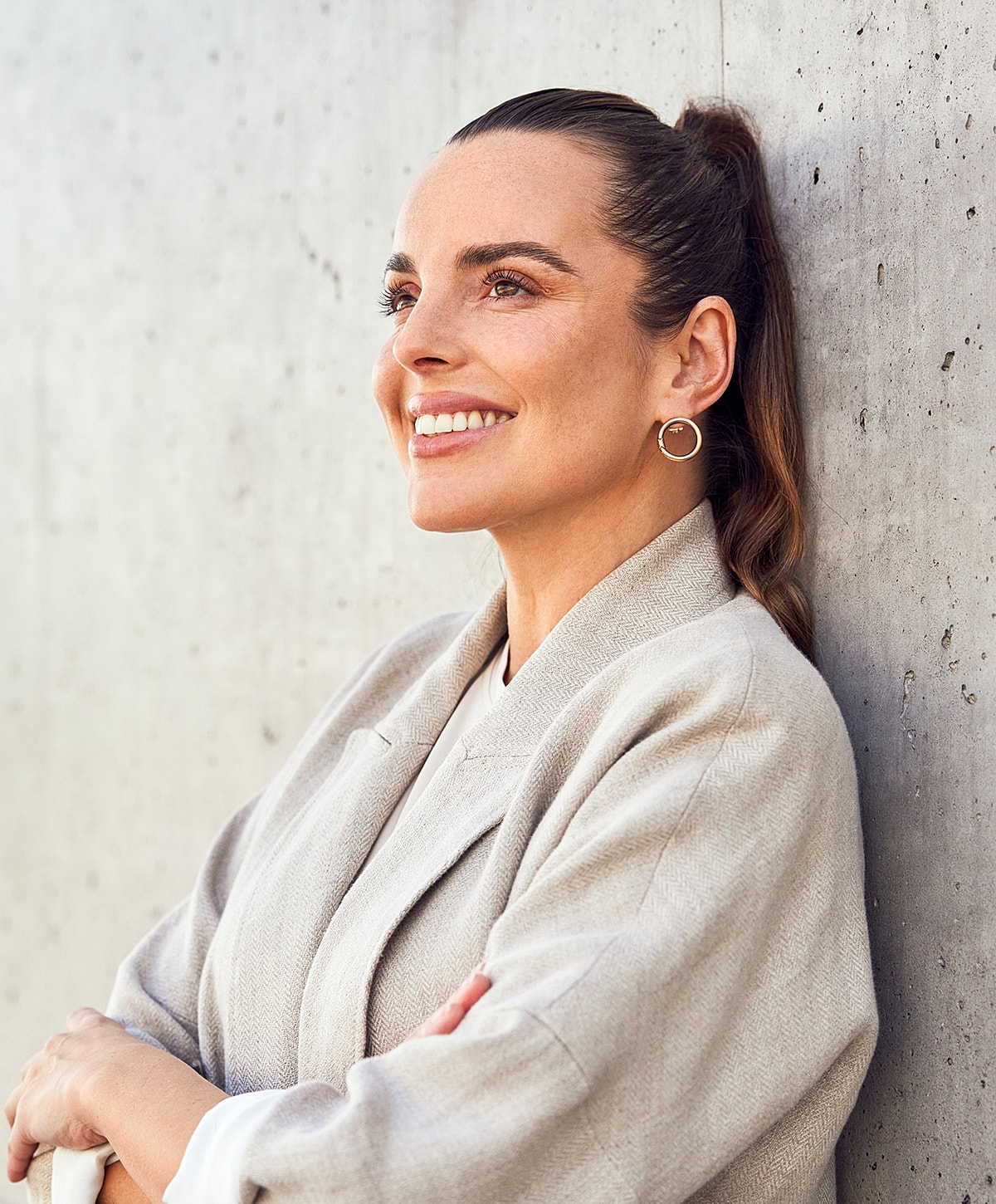 Smiling woman leaning against concrete wall.